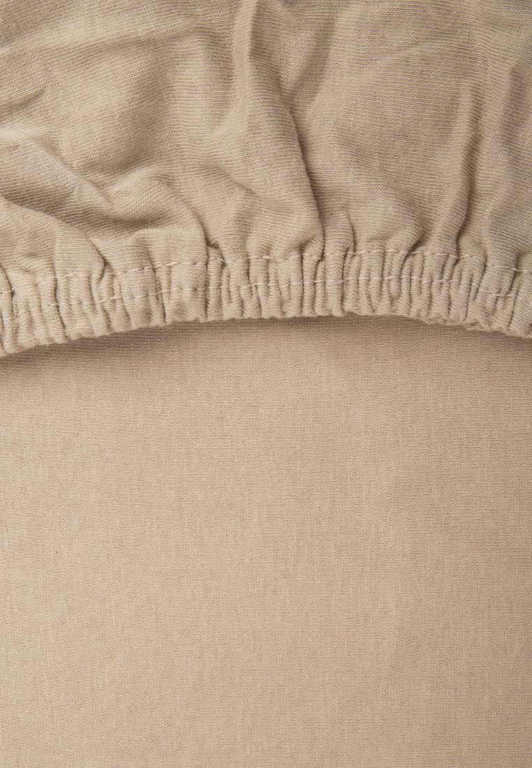 Tessuto beige con una superficie texturizzata, caratterizzato da un bordo elastico arricciato. Il materiale è morbido e liscio, ideale per un uso su misura.