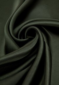 Donkergroene satijnen stof met een zachte textuur, die zachte plooien en een glanzende glans laat zien, typerend voor hoogwaardige textielmaterialen.