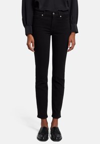 Vaqueros ajustados negros con un diseño clásico de cinco bolsillos, cierre de botón y un ligero stretch para mayor comodidad. Textura suave con una silueta entallada.