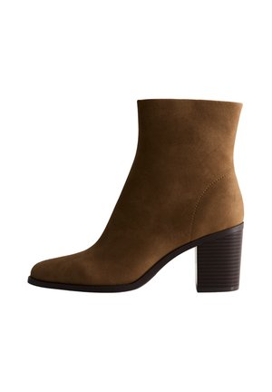 Stivale alla caviglia in suede marrone con punta arrotondata, tacco a blocco resistente e texture liscia. Presenta un design semplice senza elementi hardware visibili.