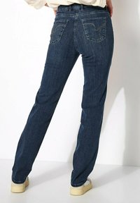 Jean en denim bleu foncé avec une coupe droite. Les caractéristiques incluent deux poches arrière avec des coutures décoratives et une taille haute.