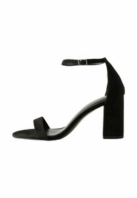 Sandale noire en daim à talon haut avec un talon bloc chunky, une fine sangle avant et une sangle de cheville avec une boucle en métal pour l'ajustement.