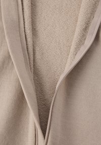 Beige zip-up hoodie met een zachte, gestructureerde binnenkant. De stof heeft een gladde buitenlaag en een comfortabele, lussenvoering aan de binnenkant.