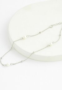 Bracciale in argento con perle bianche e piccoli pallini in argento, caratterizzato da un design delicato e chiusura regolabile.
