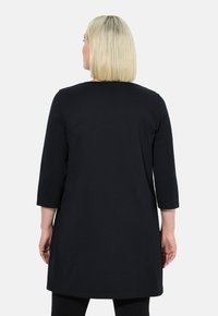 Schwarze Tunika mit Dreiviertelärmel, aus weichem Stoff gefertigt, mit einem schlichten Design und einem Saum, der unter die Hüften reicht.