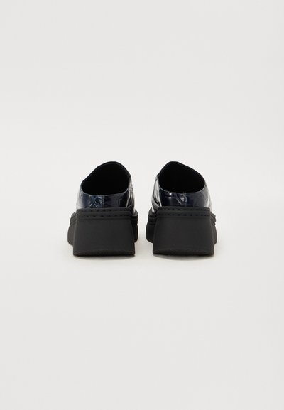 Pantofi slip-on din piele patent neagră, cu talpă din cauciuc masiv, având o textură netedă și un design cu spate rotunjit.