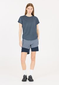 Kortärmad, mörkblå randig t-shirt kombinerad med ljusgrå och marinblå shorts. Bärs med svarta sneakers och vita strumpor, stående mot en vit bakgrund.