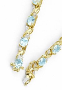 Zelta krāsas rokassprādze ar maiņām gaiši zilām ovālām akmeņiem un nelielām caurspīdīgām detaļām, ar savērptu dizainu un drošu aizdari.