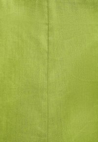 Linnen stof in een heldergroene kleur, met een gladde structuur en zichtbare stiksels langs de middennaad.