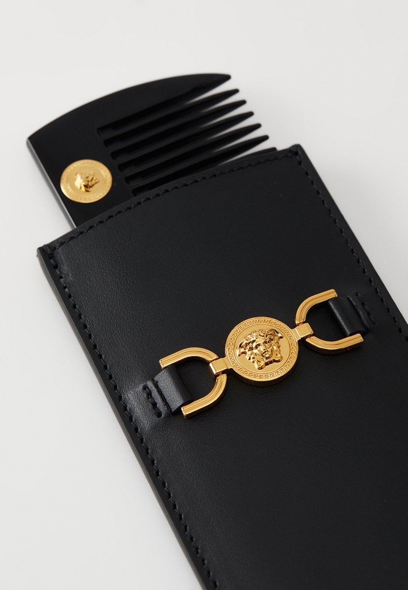 Schwarzes Lederkamm-Etui mit einer goldenen Löwenmedaille und Schnalle. Enthält einen schwarzen Kunststoffkamm mit breiten Zähnen zum Pflegen.