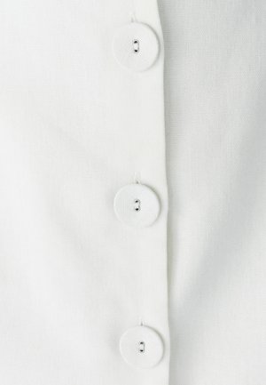 Camisa blanca de botones con cuatro botones grandes y redondos, que presenta una tela texturada y costuras visibles a lo largo de la botonera.
