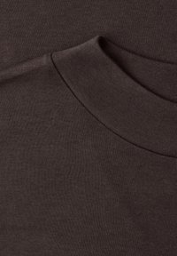 Gros plan sur un tissu marron foncé montrant un col rond plié d'un vêtement tricoté.
