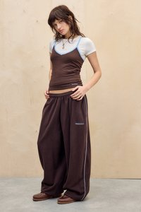 Brown tank top with light blue accents layered over a white t-shirt, paired with oversized brown sweatpants featuring blue side stripes.