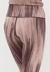 Leggings feitos de um tecido elástico e texturizado em tons de rosa claro e castanho escuro, com um padrão riscado e um detalhe de cintura alta.