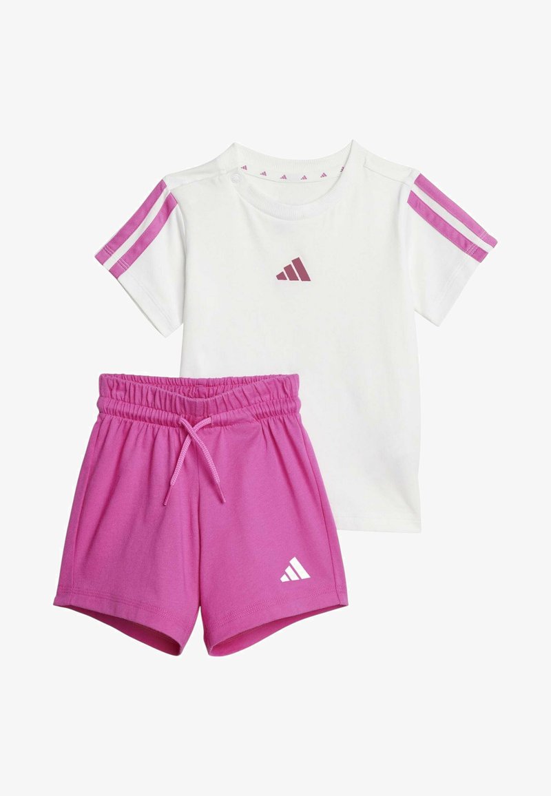 Camiseta blanca de algodón con rayas rosas en los hombros y logo, combinada con pantalones cortos rosas que tienen una cinturilla elástica y detalle de logo.