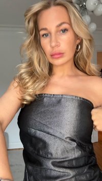 Black denim strapless dress with a fitted silhouette and subtle sheen. The fabric has a textured finish with slight wrinkling and folds.