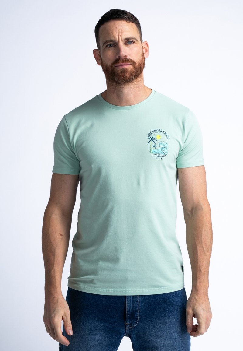 Camiseta de algodón verde menta con mangas cortas, cuello redondo y un gráfico impreso que presenta palmeras y un sol en el lado izquierdo del pecho.
