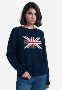 Maglione lavorato a maglia blu navy con un design centrale della Union Jack in rosso, bianco e blu. Vestibilità comoda con polsini e orlo a coste.