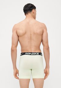 Pánske boxerky NIKESNIKE svetlozelenej farby s čiernym elastickým pásom, na ktorom je v bielej farbe vytlačený názov značky, hladká textúra.