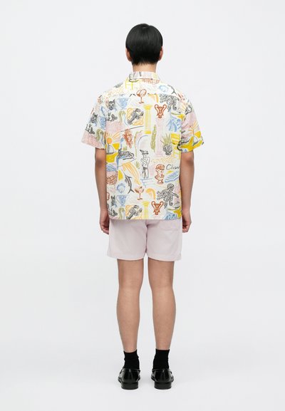 Πουκάμισο με κοντά μανίκια και γιακά, που διαθέτει πολύχρωμο σχεδιασμό με διάφορα μοτίβα. Φορεμένο με ανοιχτό ροζ σορτς και μαύρα παπούτσια.