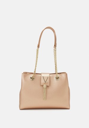 Sac à main en or rose avec cuir texturé, deux poignées (une en cuir, une en chaîne dorée), fermeture magnétique et un détail de frange décoratif.