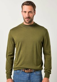 Olivegrüner Pullover aus weichem Strickstoff mit Rundhalsausschnitt und langen Ärmeln, kombiniert mit blauen Jeans und einem braunen Gürtel.
