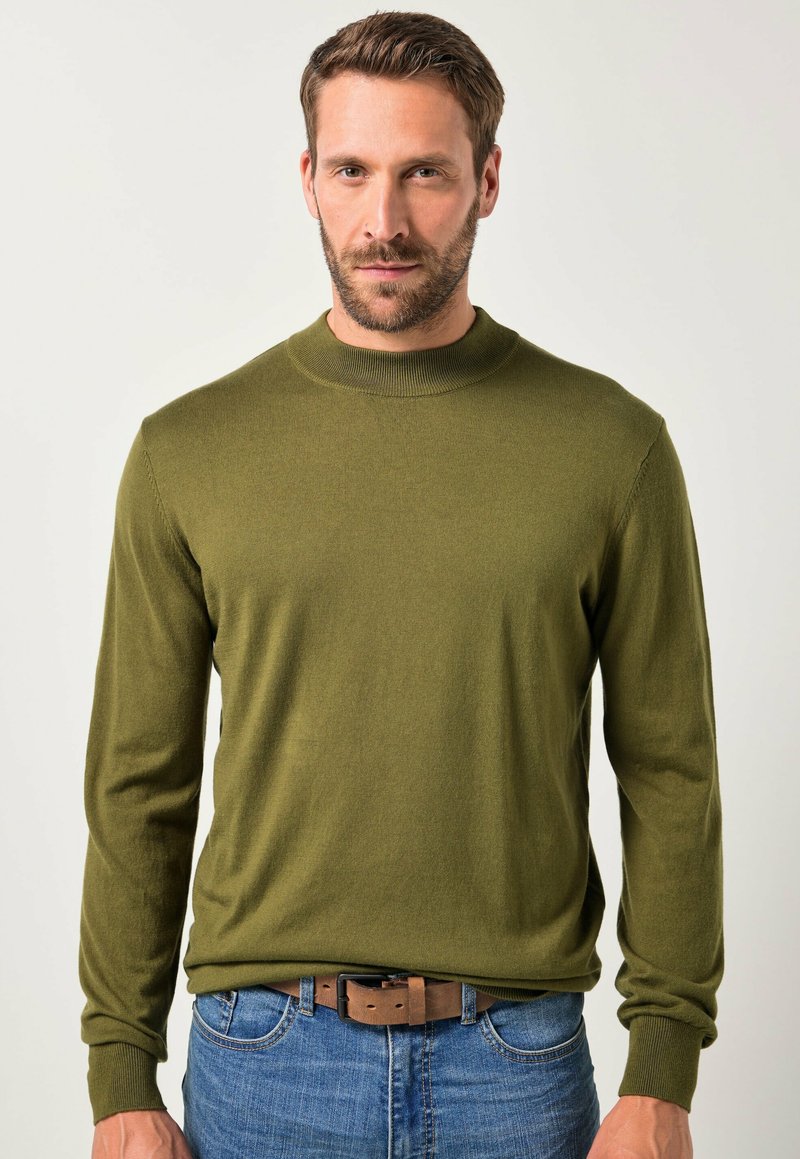 Olivegrüner Pullover aus weichem Strickstoff mit Rundhalsausschnitt und langen Ärmeln, kombiniert mit blauen Jeans und einem braunen Gürtel.