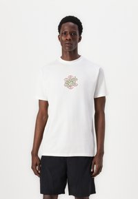 White cotton t-shirt featuring a colorful graphic logo "Santa Cruz" at the center, crew neck, and short sleeves, paired with black shorts.