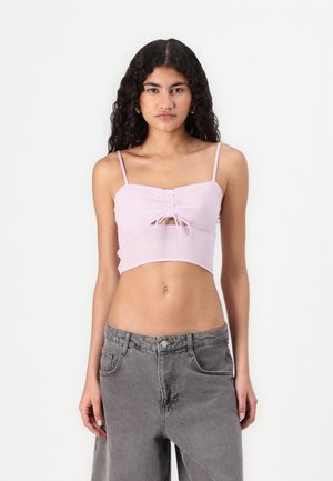 Lilac crop top with spaghetti straps, textured fabric, gathered front with a keyhole opening, paired with gray wide-leg jeans.