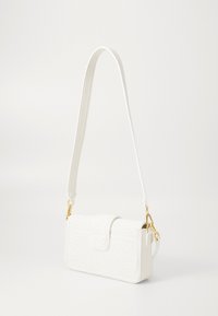 Sac à main blanc texturé avec fermeture à rabat, bandoulière ajustable, accents en matériel doré et forme rectangulaire. Présente un subtil motif tissé.