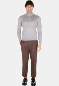 Maglione grigio con collo zip, design aderente, tessuto a costine; pantaloni marroni su misura, dettagli delle pieghe e scarpe nere. Stile semplice e pulito.
