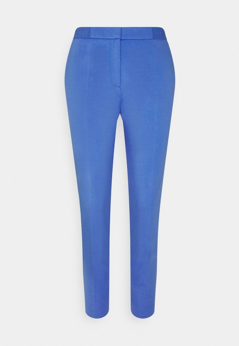 Pantalon bleu ajusté avec une texture lisse, coupe droite et une ceinture présentant un logo en relief. Pas de poches visibles.