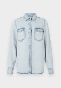 Light blue denim shirt with a pointed collar, button front, and two chest pockets. Features stitched detailing and a slightly frayed hem.