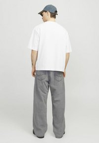 White, short-sleeve cotton t-shirt paired with gray, loose-fit denim jeans. Denim cap with a brown brim. Simple and casual styling.