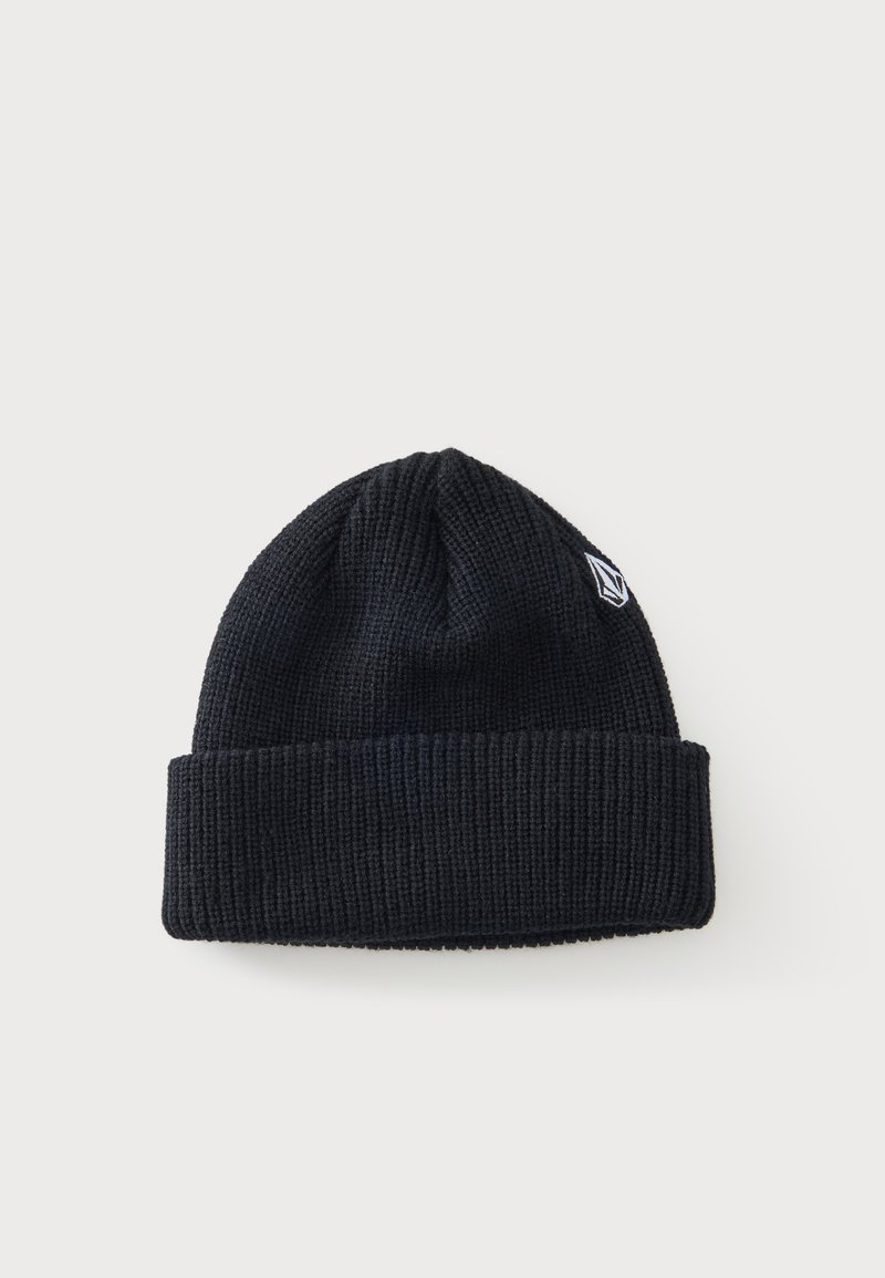 Bonnet en tricot côtelé noir avec revers plié et petit logo géométrique blanc sur le côté, sur fond clair uni.