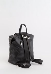 Mochila de cuero sintético negro con cierre de cremallera, base plana, asa corta y correa larga ajustable que presenta la palabra "AMIGABLE".