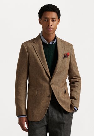 Brauner Fischgrät-Blazer aus strukturiertem Stoff, mit Reverskragen, zwei Fronttaschen und einem roten gemusterten Einstecktuch.