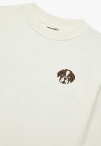 Witte sweater met geribbelde kraag, voorzien van een bruin en wit geborduurd hondenhoofd aan de voorkant. Zachte textuur, casual ontwerp.