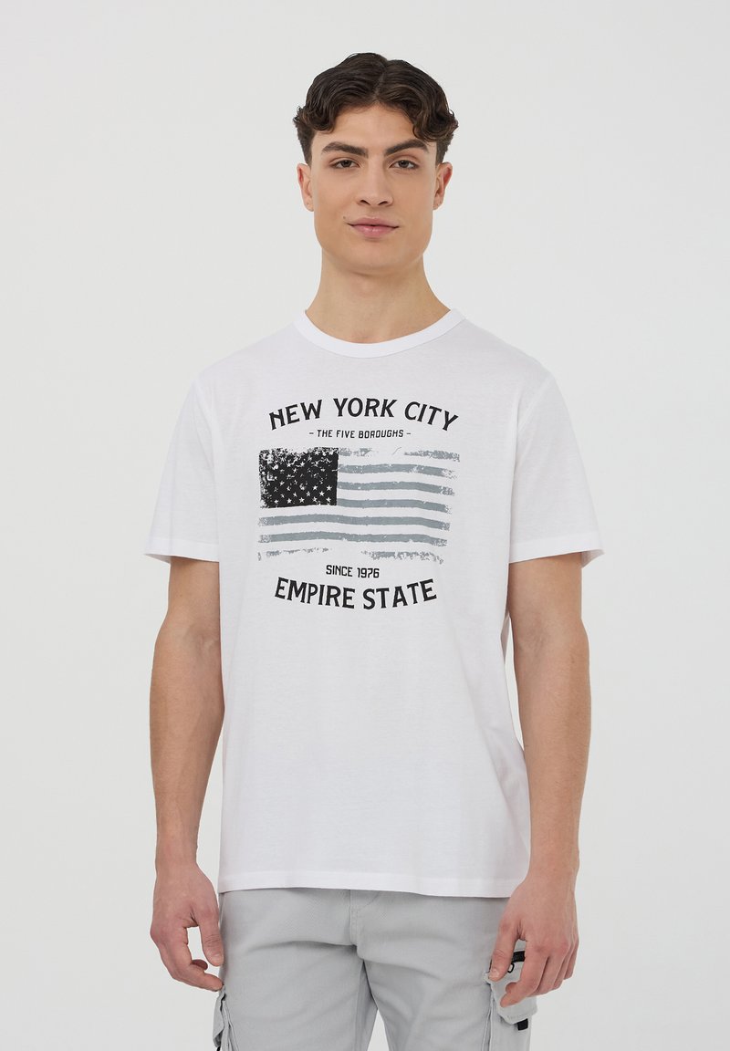 T-shirt bianca in cotone con una stampa grafica di una bandiera americana stilizzata, scritte "NEW YORK CITY" e "EMPIRE STATE", scollatura rotonda.