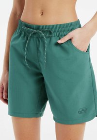 Groene, gestructureerde shorts met een elastische tailleband, trekkoord en zijzakken. Bevat een klein gedrukt logo aan de zoom.