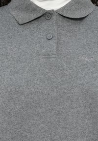 Γκρι πόλο μπλούζα από πλεκτό ύφασμα, με μαλακό γιακά, δύο γκρι κουμπιά, μια μικρή τσέπη στο στήθος και κεντητό λογότυπο στο πλάι.