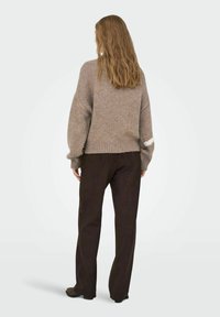 Pull en maille marron clair avec épaules tombantes et ourlet côtelé, associé à un pantalon droit marron foncé et des chaussures.