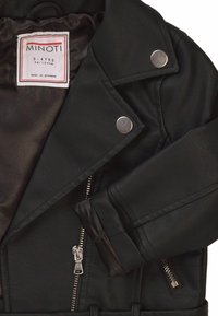 Giacca in faux pelle nera per bambini, con hardware argento, tasche con zip, colletto a revers e fodera morbida. L'etichetta indica la taglia 3-4 anni.