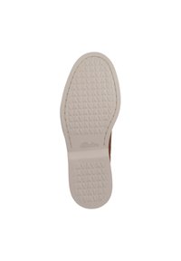 Bruine schoen met een gestructureerde bovenkant en een witte rubberen zool, voorzien van een geprofileerde loop voor grip en het "Clarks"-logo in de zool geperst.