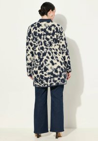 Marinblå och krämfärgad oversized kofta med ett leopardmönster, som har en texturerad tyg, långa ärmar och en rak fåll.