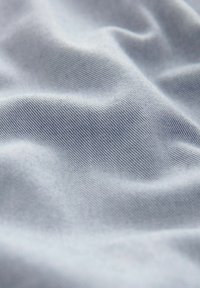Light blue fabric with a smooth texture and subtle, fine ribbing, displaying gentle waves and folds throughout the surface.