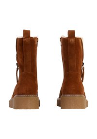 Stivaletti alla caviglia in suede marrone con finitura testurizzata, suole in gomma e cerniere laterali. Presentano un morbido rivestimento visibile nella parte superiore.