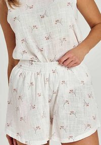 Zestaw tunika i szorty z mieszanki lnu w białym kolorze z kwiatowym wzorem. Posiada elastyczną talię oraz lekką, przewiewną tkaninę.