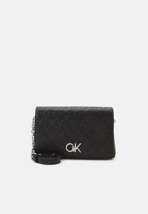 Black Calvin Klein crossbody bag with embossed logo pattern and silver CK buckle on front flap, detachable leather and chain strap.
