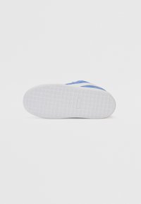 Base de ténis azul e branco, com uma sola de borracha branca texturizada com um padrão em diamante e parte superior azul perfurada para respirabilidade.